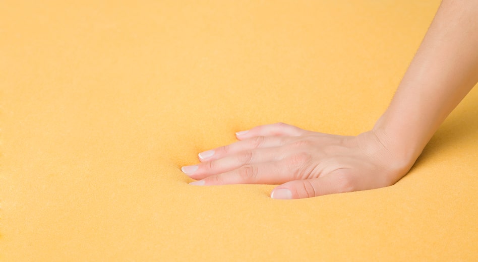 A hand presses into a foam pad