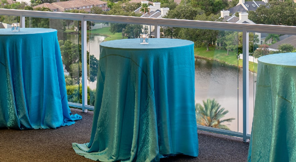 MityLite Cocktail-Tische mit Tischdecken bedeckt mit einem Balkon-Hintergrund