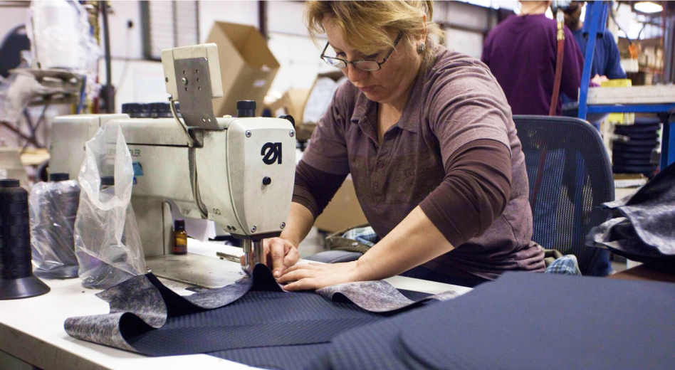 Factory worker sewing upholstery for banquet seating