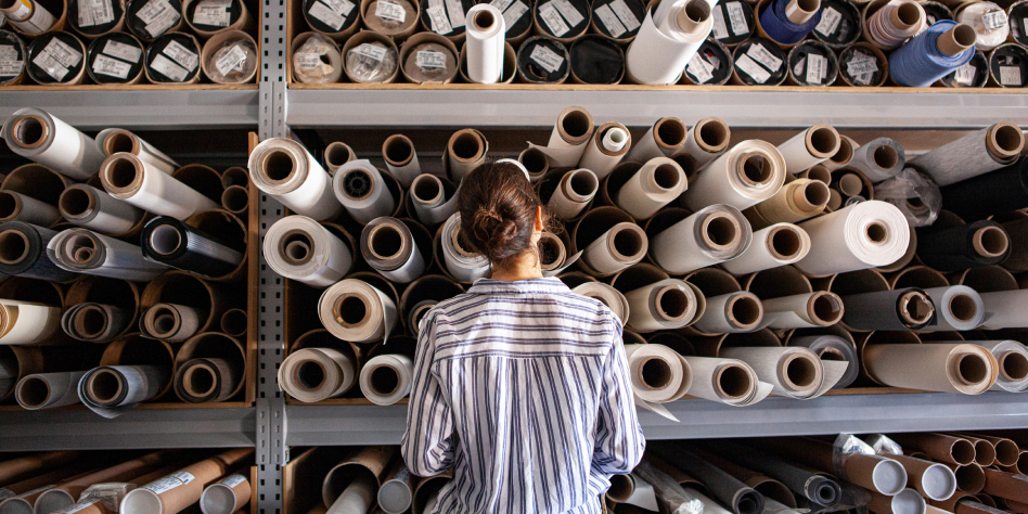 Woman browsing a large wall of upholstery and fabric bolts