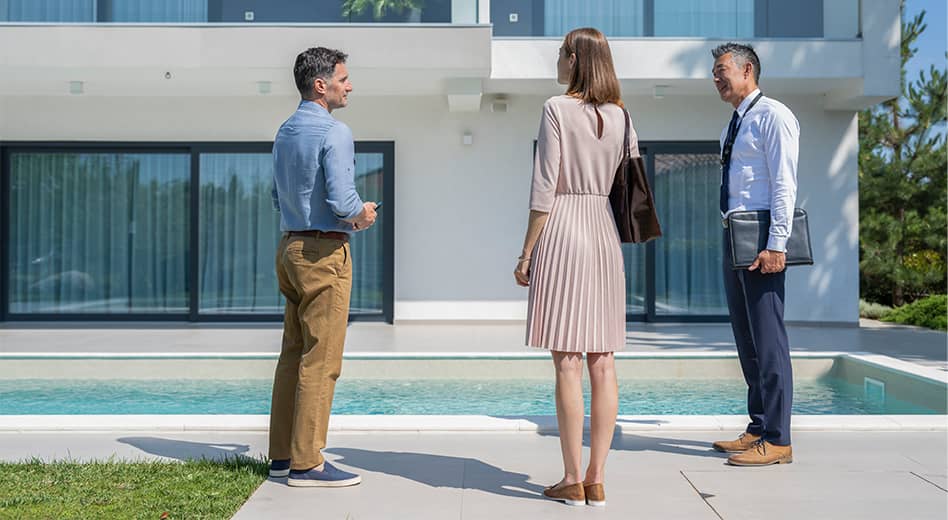 Pessoas vestidas profissionalmente reunidas e conversando perto de uma piscina em um grande espaço ao ar livre