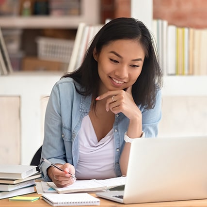 Jeune femme utilisant un ordinateur et prenant des notes