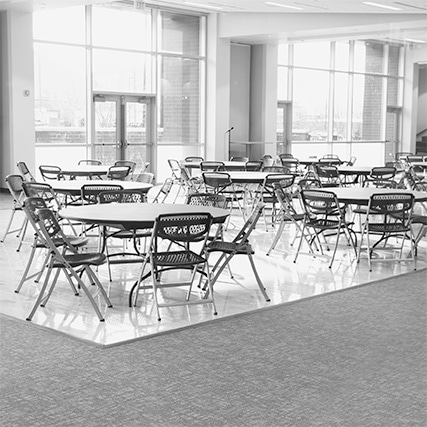 image en niveaux de gris de chaises pliantes en plastique entourant des tables