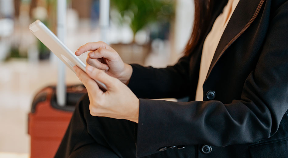 Close up of a traveler using a tablet with luggage in the background