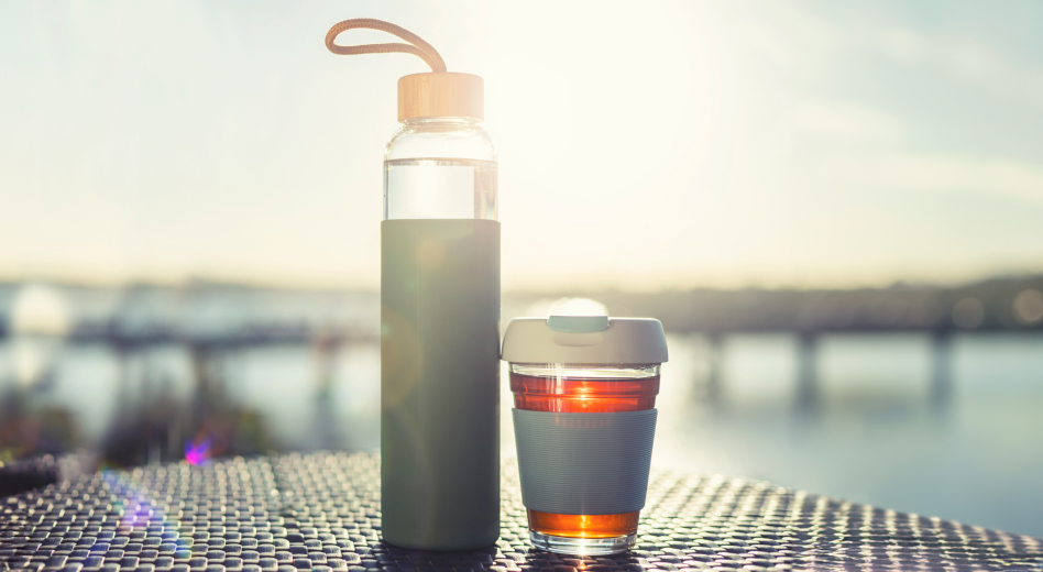 Glass water bottle and travel coffee mug on outdoor patio at resort