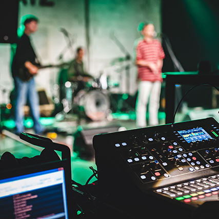 Audio equipment with performers on stage in the background