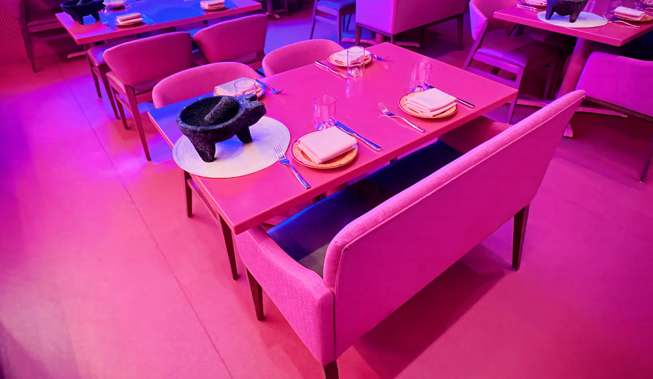 Upholstered, modern benches at a tables in a vibrantly lit restaurant