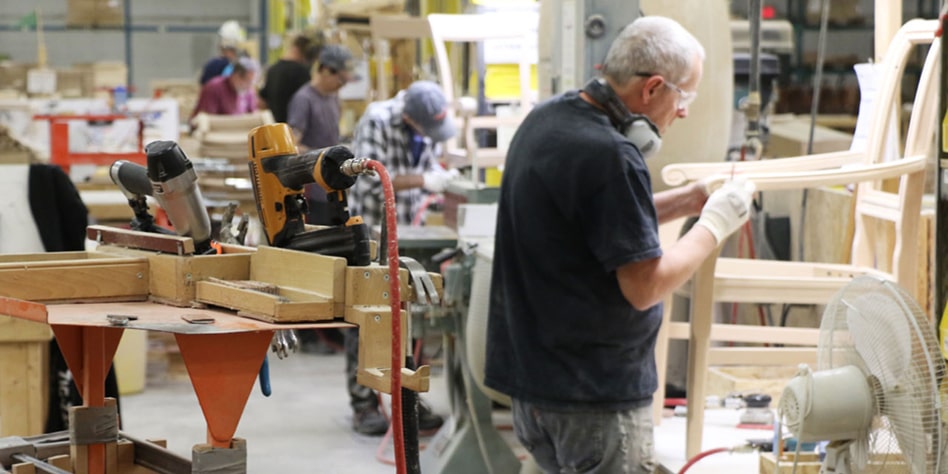 Mann baut Holzstuhl in einer Fabrik