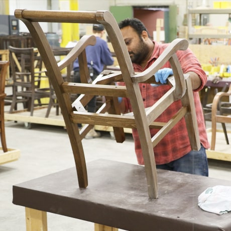 A wooden chair frame is being inspected after staining and wiping process