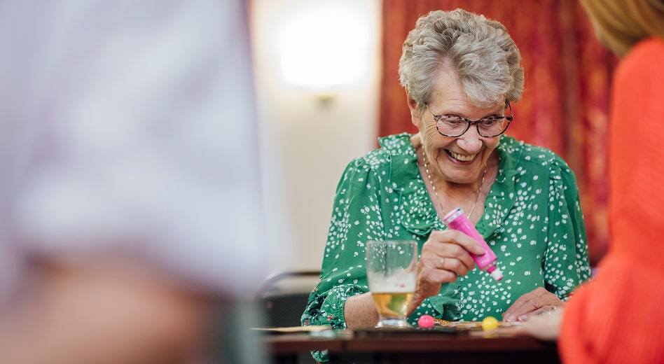 An elderly woman smiling while marking her bingo card.