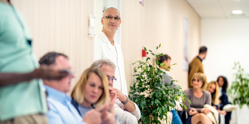 A doctor looks into a crowded hospital waiting room.