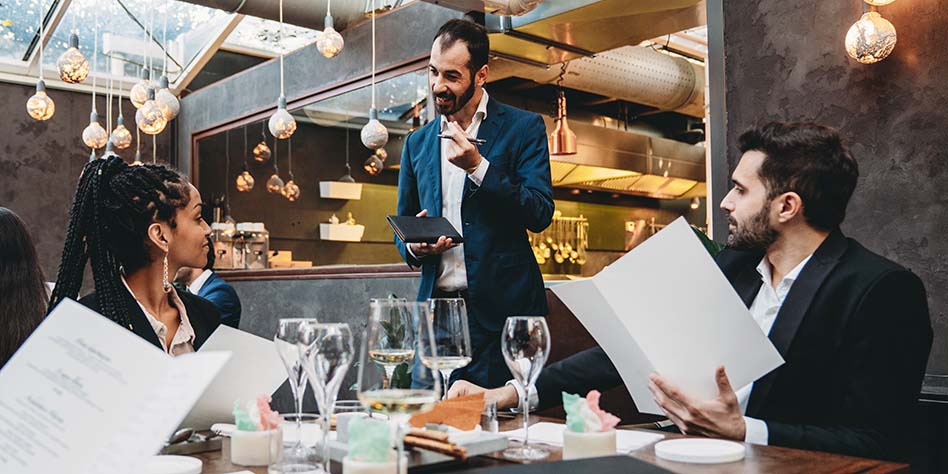 Waiter in conversation with customers in an upscale restaurant