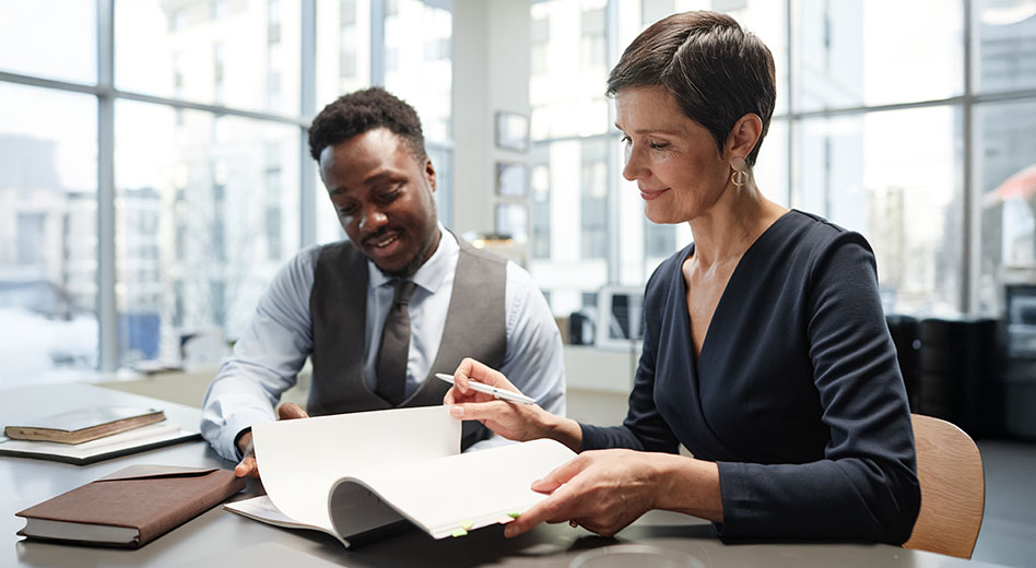 Mature business woman signing documents alongside a colleague
