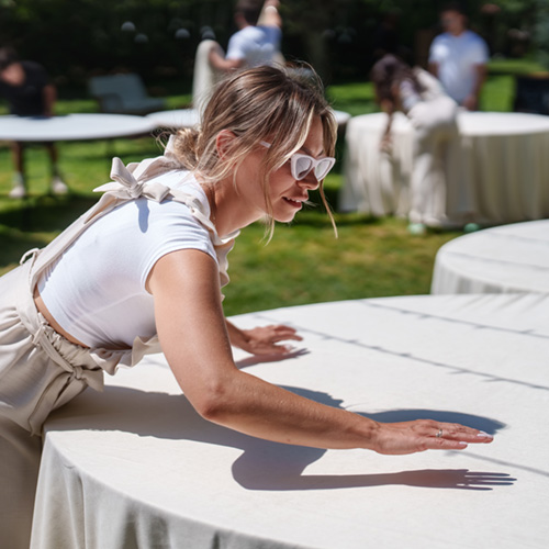  Uma coordenadora de eventos ajudando a arrumar as toalhas de mesa para um evento ao ar livre.