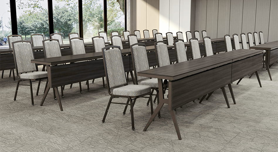 Cadeiras de metal para banquetes dispostas com mesas de conferência.