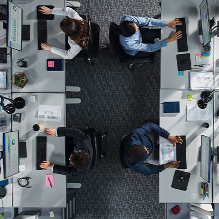Vista aérea de los empleados sentados en una zona de escritorios compartida.