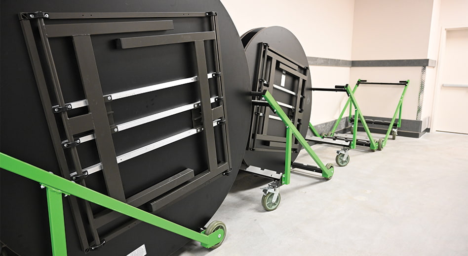 Tables stored neatly into carts lined against a wall