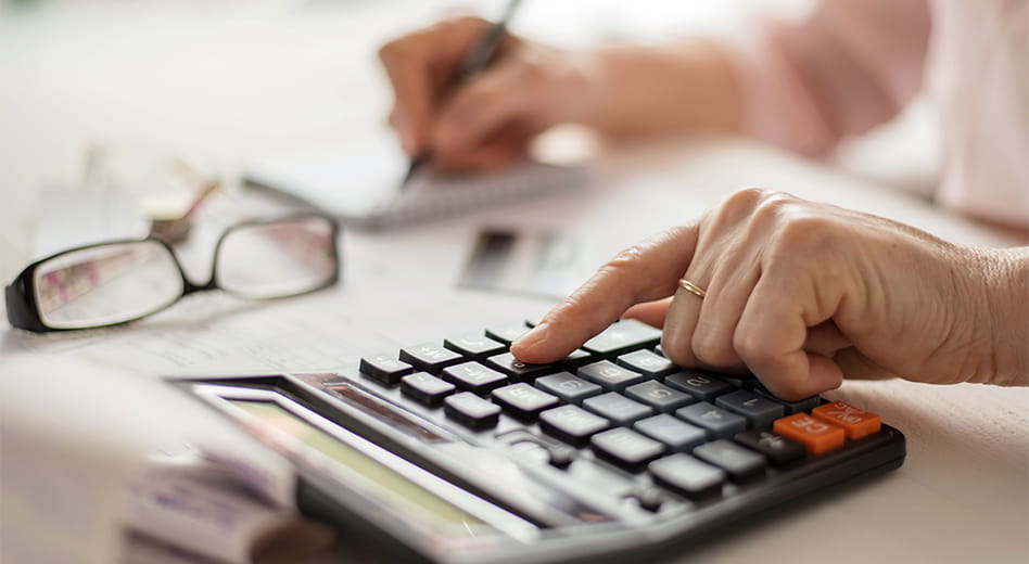 Close up of a hand typing on a calculator