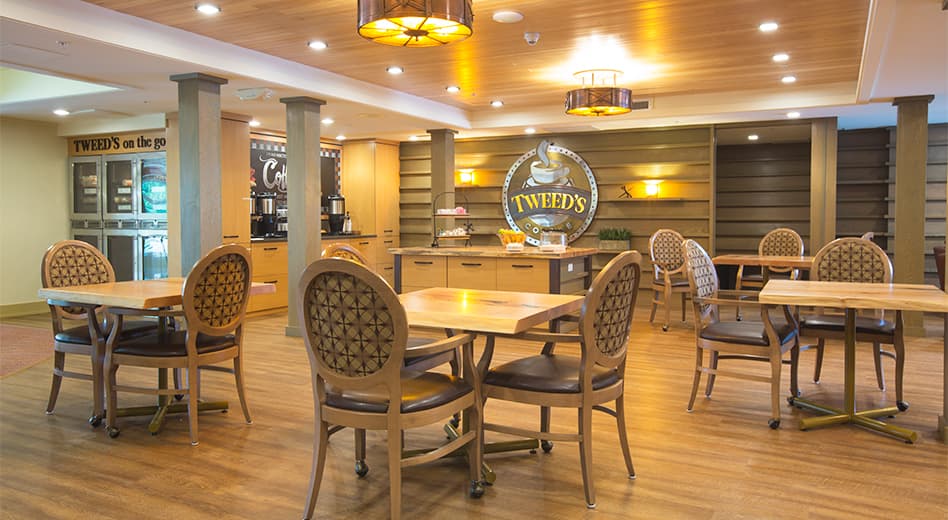 A coffee shop within a hotel using wooden furniture in a warmly designed space